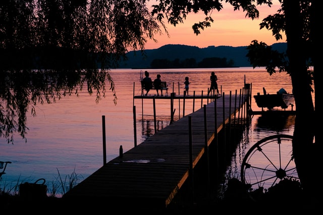 People sitting by the river during a sunset