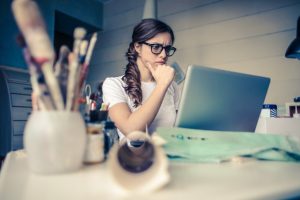 A woman thinking in front of a laptop.