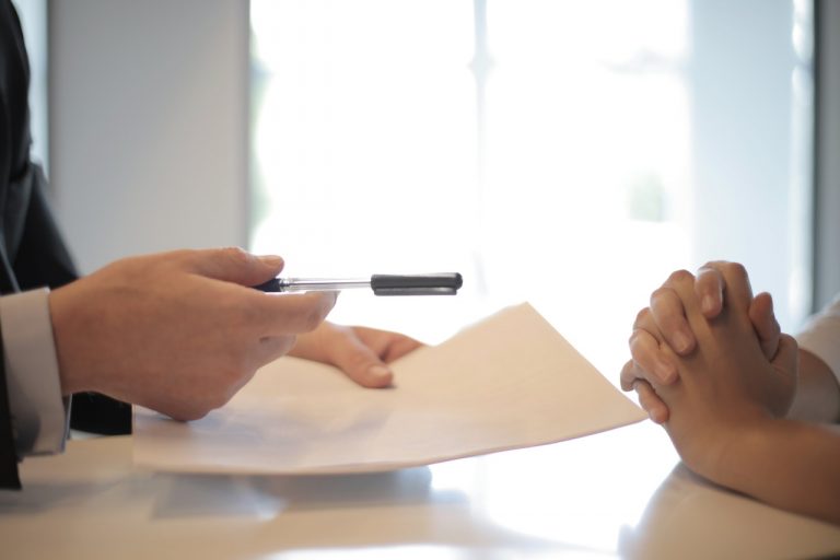 A businessman giving a woman a document to sign for investing in Secaucus real estate.