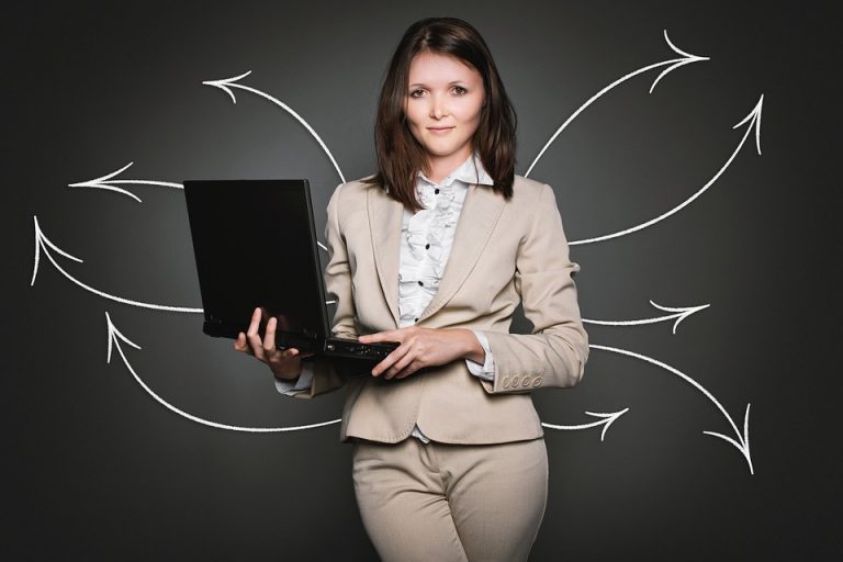 A young girl holding a laptop in her hands.